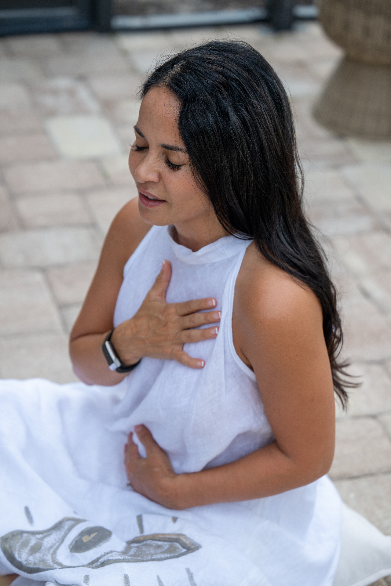 Nevriye Yesil with eyes closed, hands at heart and belly in stillness